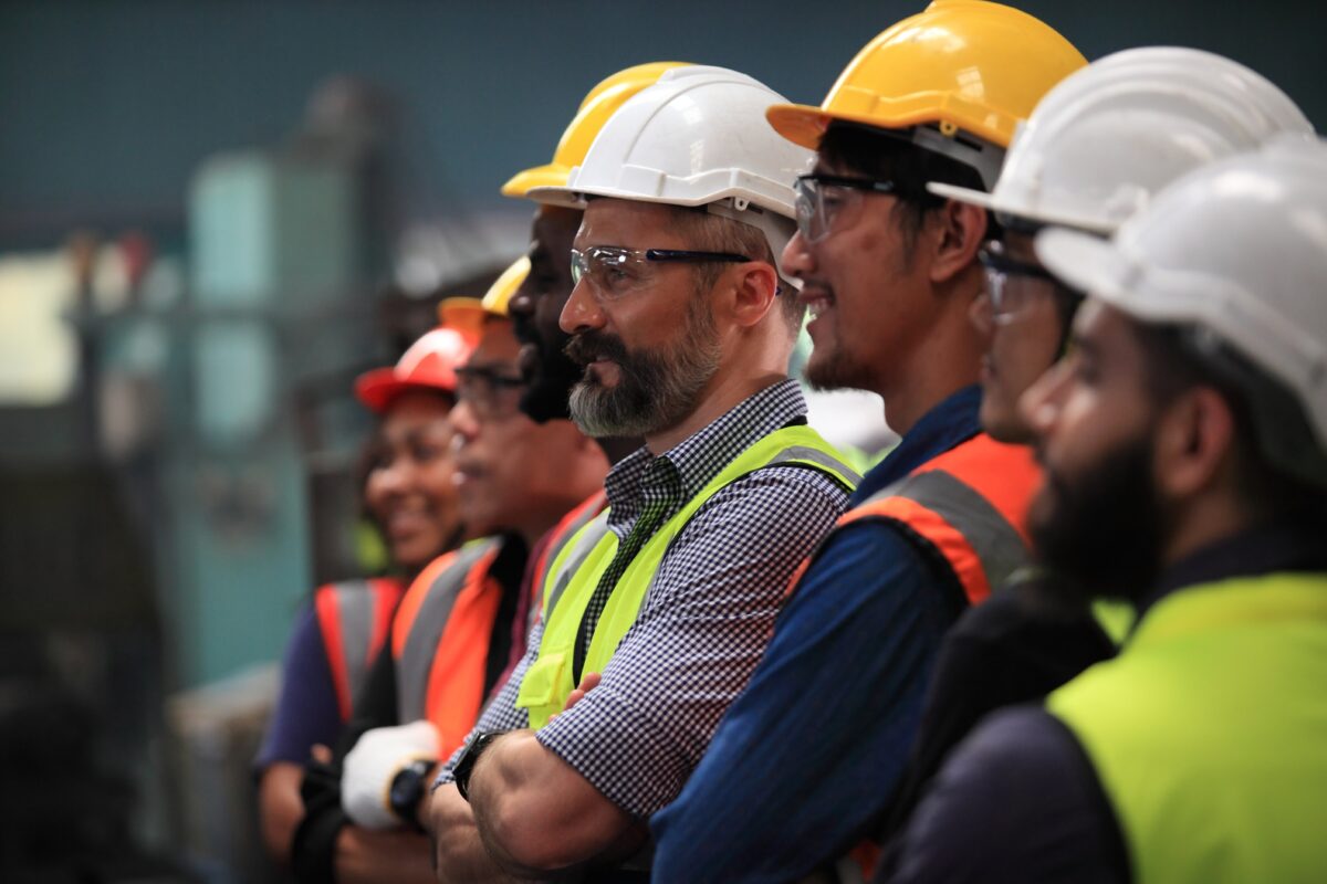 Persone in fila con casco di sicurezza per promuovere un corso gratuito salute e sicurezza di lavoratori - CFI Formazione